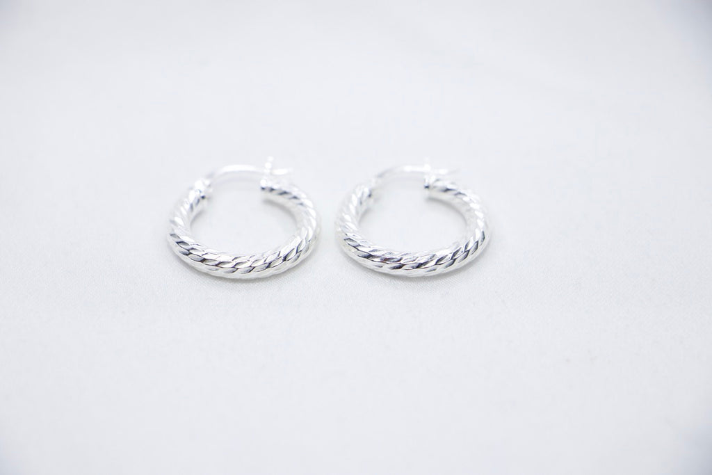 A Braided Radiance Hoop Earrings in sterling silver, featuring a sophisticated braided design that reflects light for a chic and radiant look, front views. 