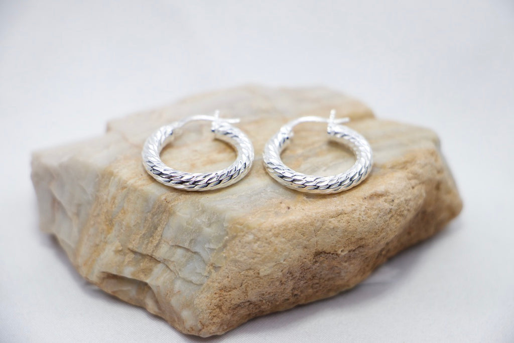 A Braided Radiance Hoop Earrings in sterling silver, featuring a sophisticated braided design that reflects light for a chic and radiant look, rock views. 