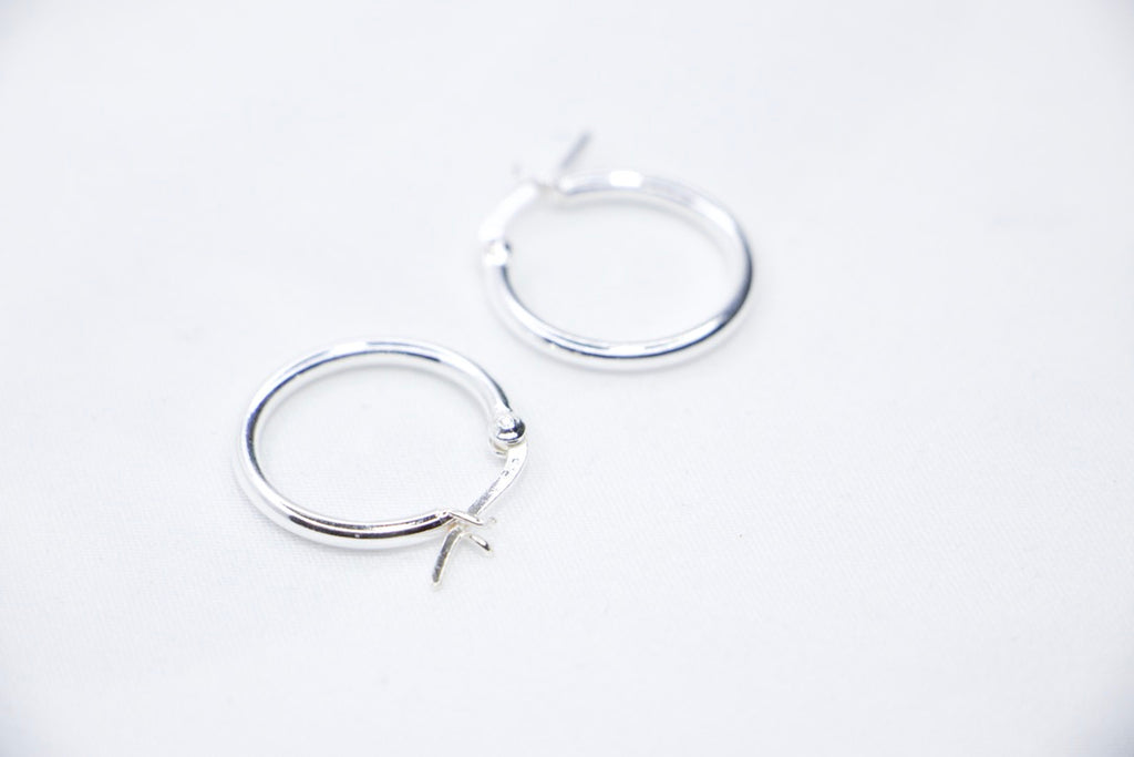 Sterling silver Eternal Grace Hoop Earrings featuring a smooth, polished circular design with an X-shaped closure for a unique, elegant look, side view.
