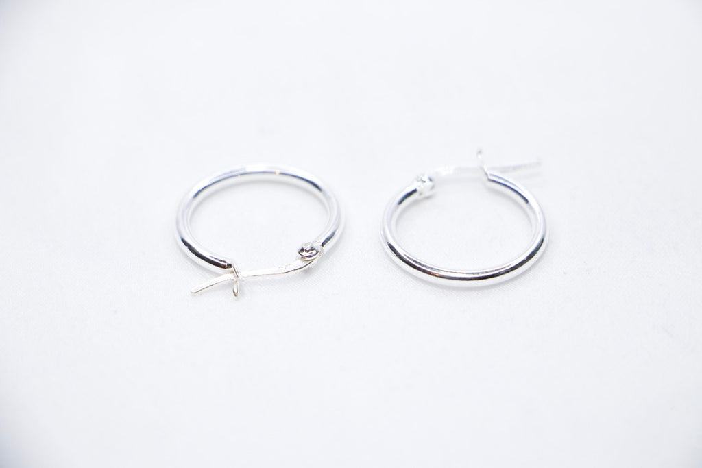 Sterling silver Eternal Grace Hoop Earrings featuring a smooth, polished circular design with an X-shaped closure for a unique, elegant look, side view.