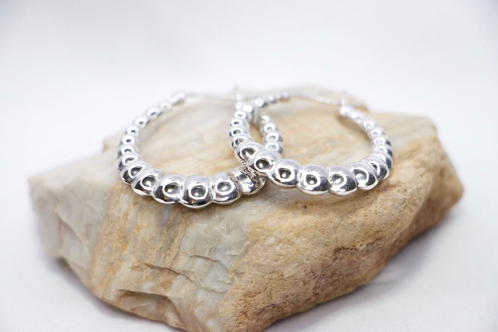Lustrous Ripple Hoops in 925 sterling silver, featuring a sculpted, bubble-textured design with a high-polish finish, rock view. 