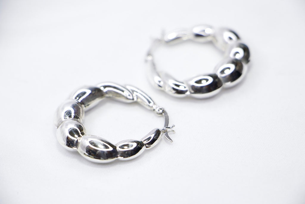 A close-up of sterling silver Luxe Bean Hoop Earrings, designed with smooth, curved shapes that form a modern, elegant hoop sides view.
