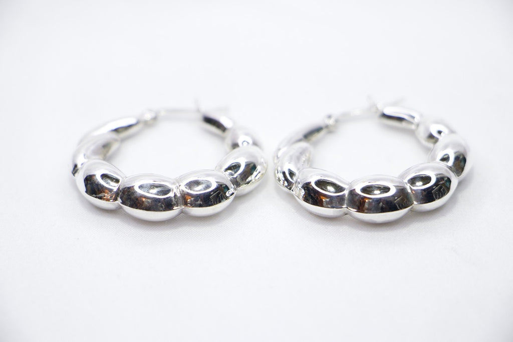 A close-up of sterling silver Luxe Bean Hoop Earrings, designed with smooth, curved shapes that form a modern, elegant hoop front view.