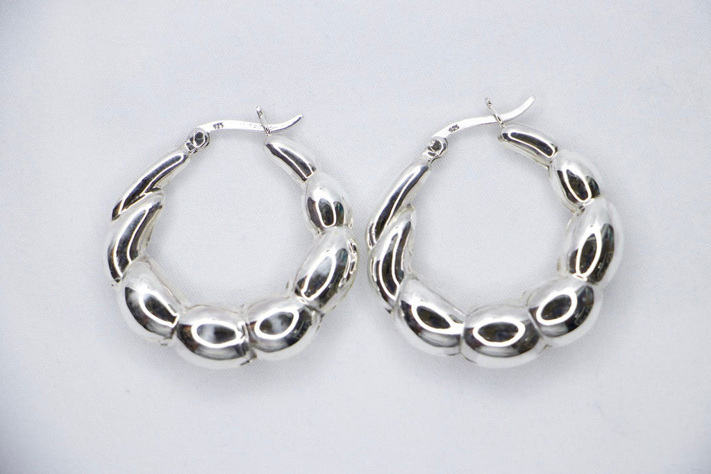 A close-up of sterling silver Luxe Bean Hoop Earrings, designed with smooth, curved shapes that form a modern, elegant hoop top view.