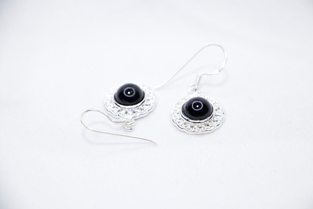 Midnight Elegance Drop Earrings featuring a black onyx gemstone encircled by intricate silver filigree, with a secure hook closure for an elegant look, side view.