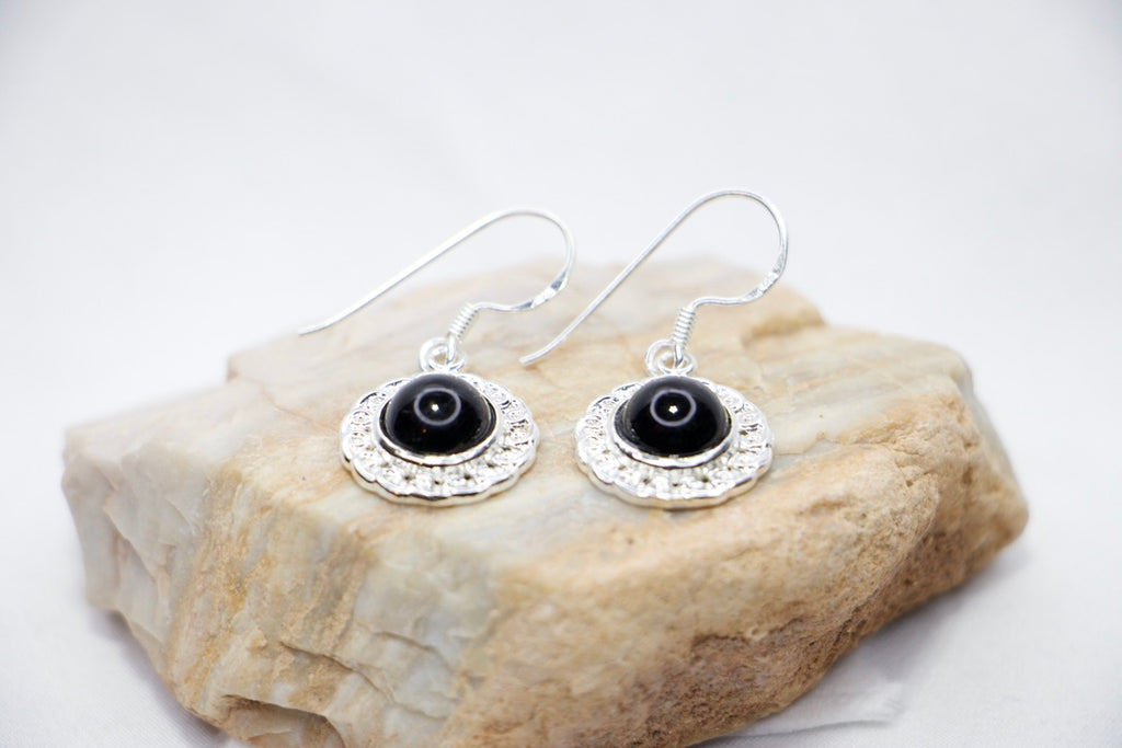 Midnight Elegance Drop Earrings featuring a black onyx gemstone encircled by intricate silver filigree, with a secure hook closure for an elegant look, rock view.
