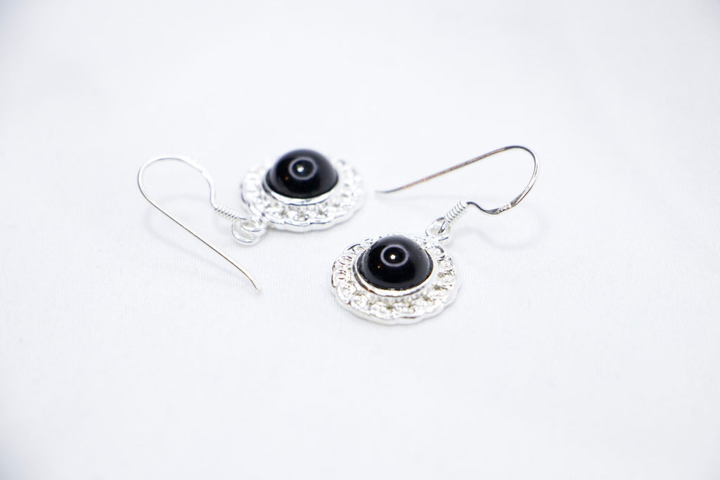 Midnight Elegance Drop Earrings featuring a black onyx gemstone encircled by intricate silver filigree, with a secure hook closure for an elegant look, side view.