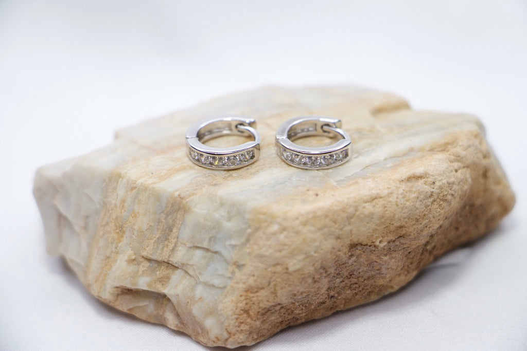 Sterling silver huggie hoop earrings with cubic zirconia, lightweight, hypoallergenic, elegant front rock view.