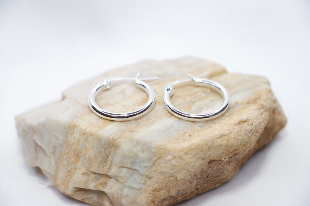 A close-up of sterling silver Radiant Simplicity Hoop Earrings featuring smooth, polished, and circular design for an elegant and classic look rock view.