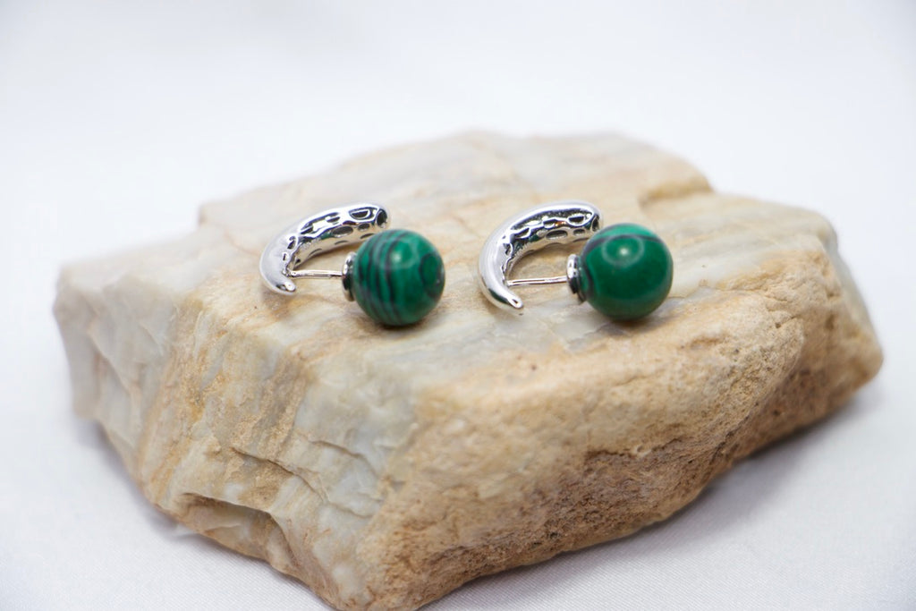 Close-up of Serpentine Dream Malachite Earrings featuring vibrant green malachite spheres set in a curved rock view.