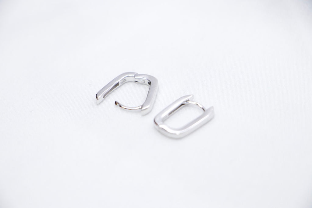 A pair of Sleek Seduction Huggie Hoops in 925 sterling silver, featuring a modern rectangular design with a high-polish finish, front open view.