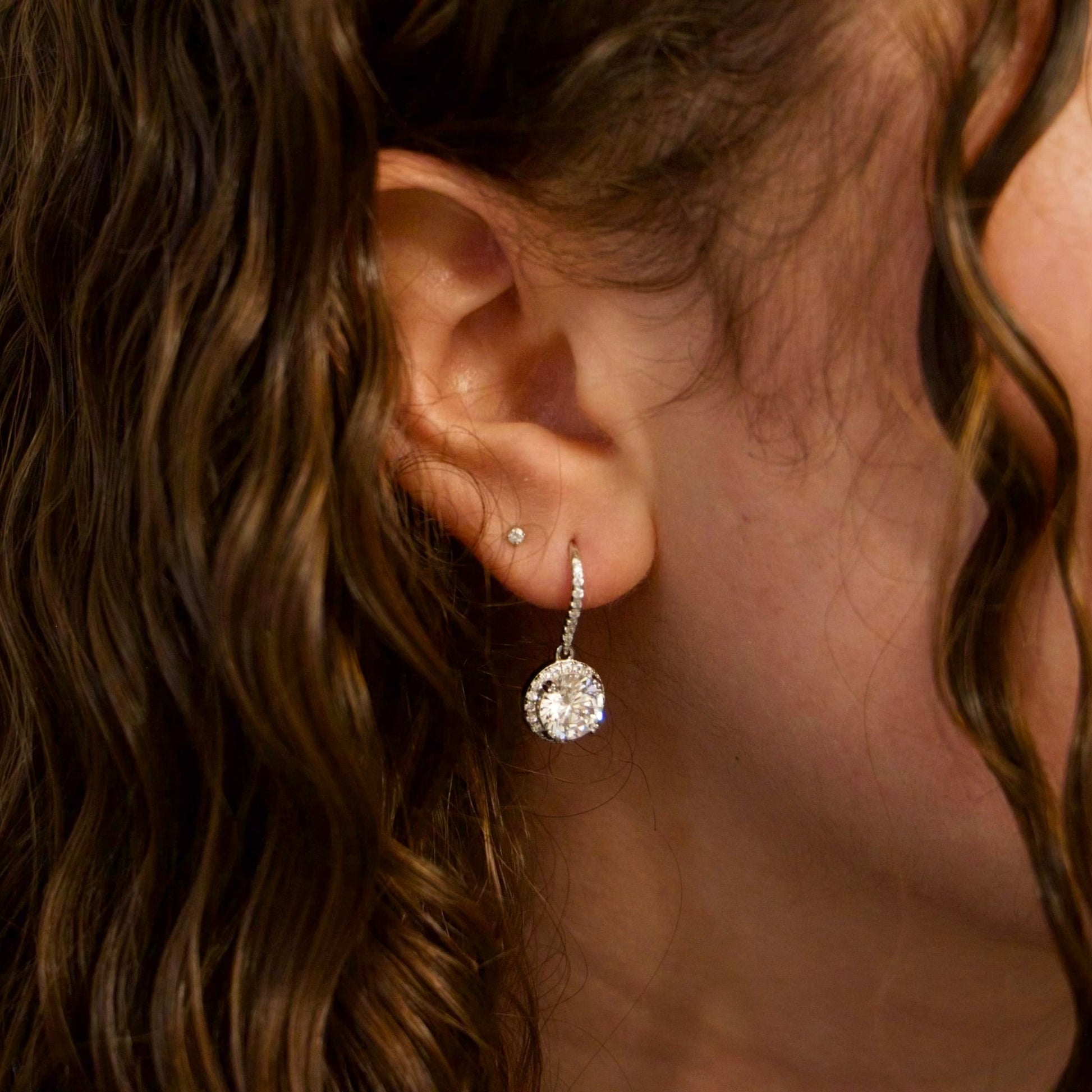 Sterling Silver Halo Crystal Dangle Earrings on a woman's ear. 