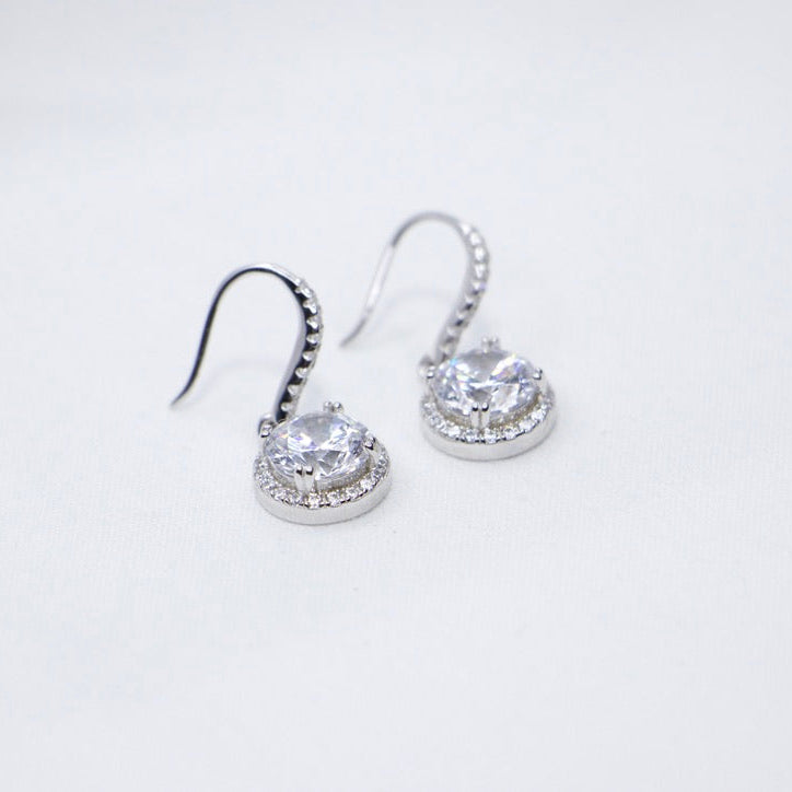 Sterling Silver Halo Crystal Dangle Earrings on counter top. 