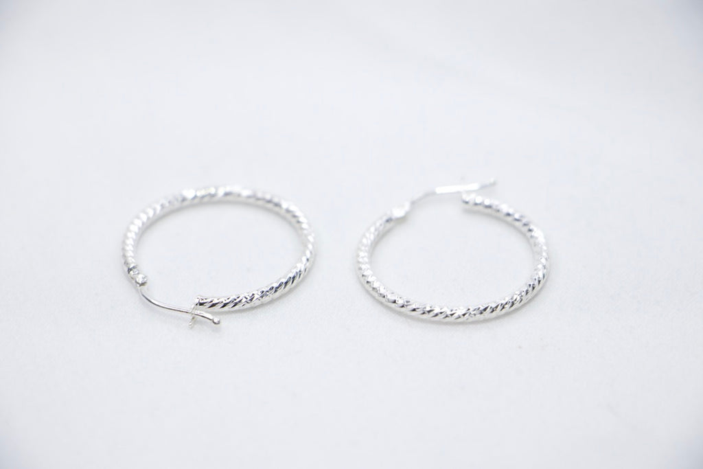 A close-up of sterling silver Woven Elegance Hoop Earrings featuring an intricate woven texture side views.