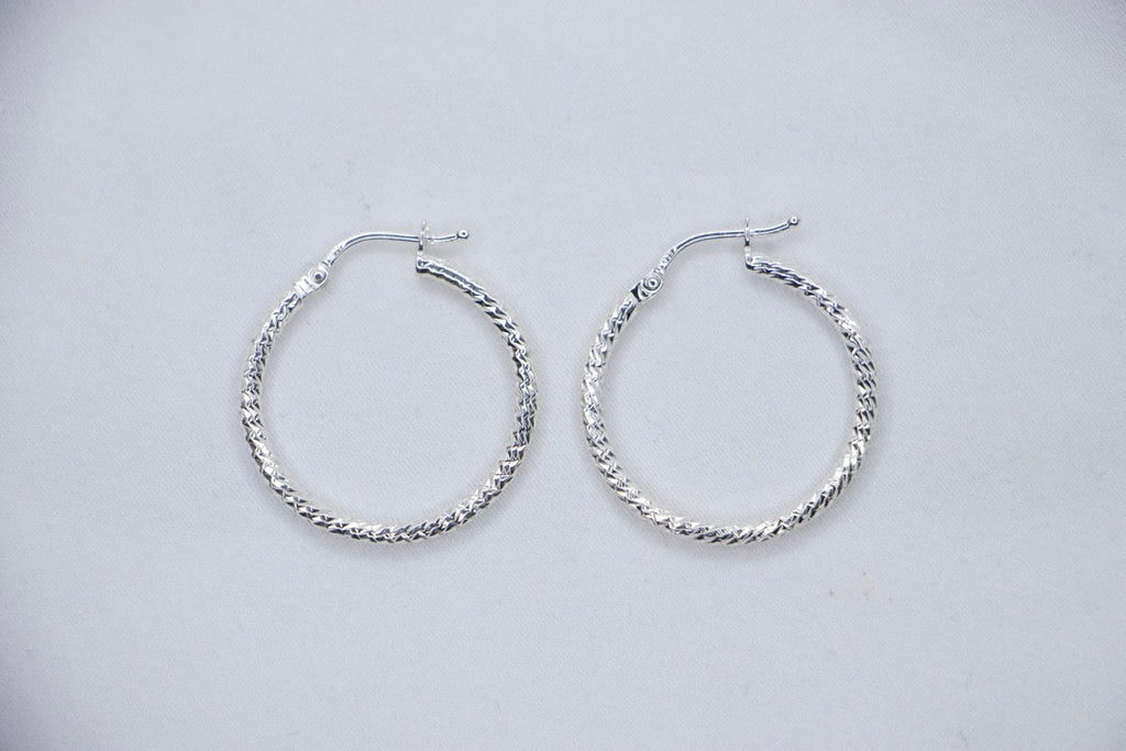 A close-up of sterling silver Woven Elegance Hoop Earrings featuring an intricate woven texture top views.